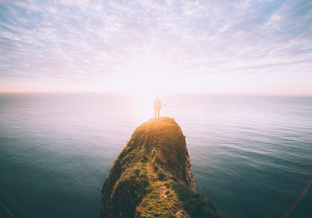 man-standing-alone-on-a-cliff-at-sunrise